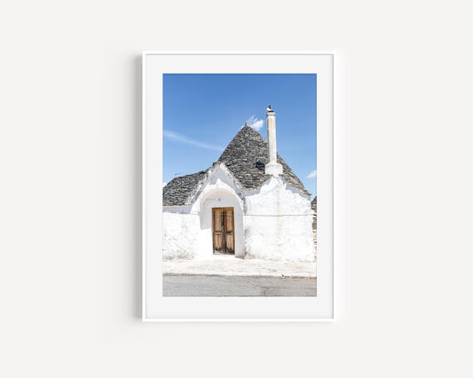 Vertical photo of trullo doorway and rooftop in Alberobello, Italy with stucco walls and blue sky – Mediterranean wall art