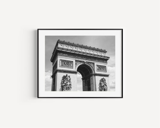 Black and white photograph of the Arc de Triomphe in Paris, taken from the Champs Elysées with strong architectural lines and soft contrast.