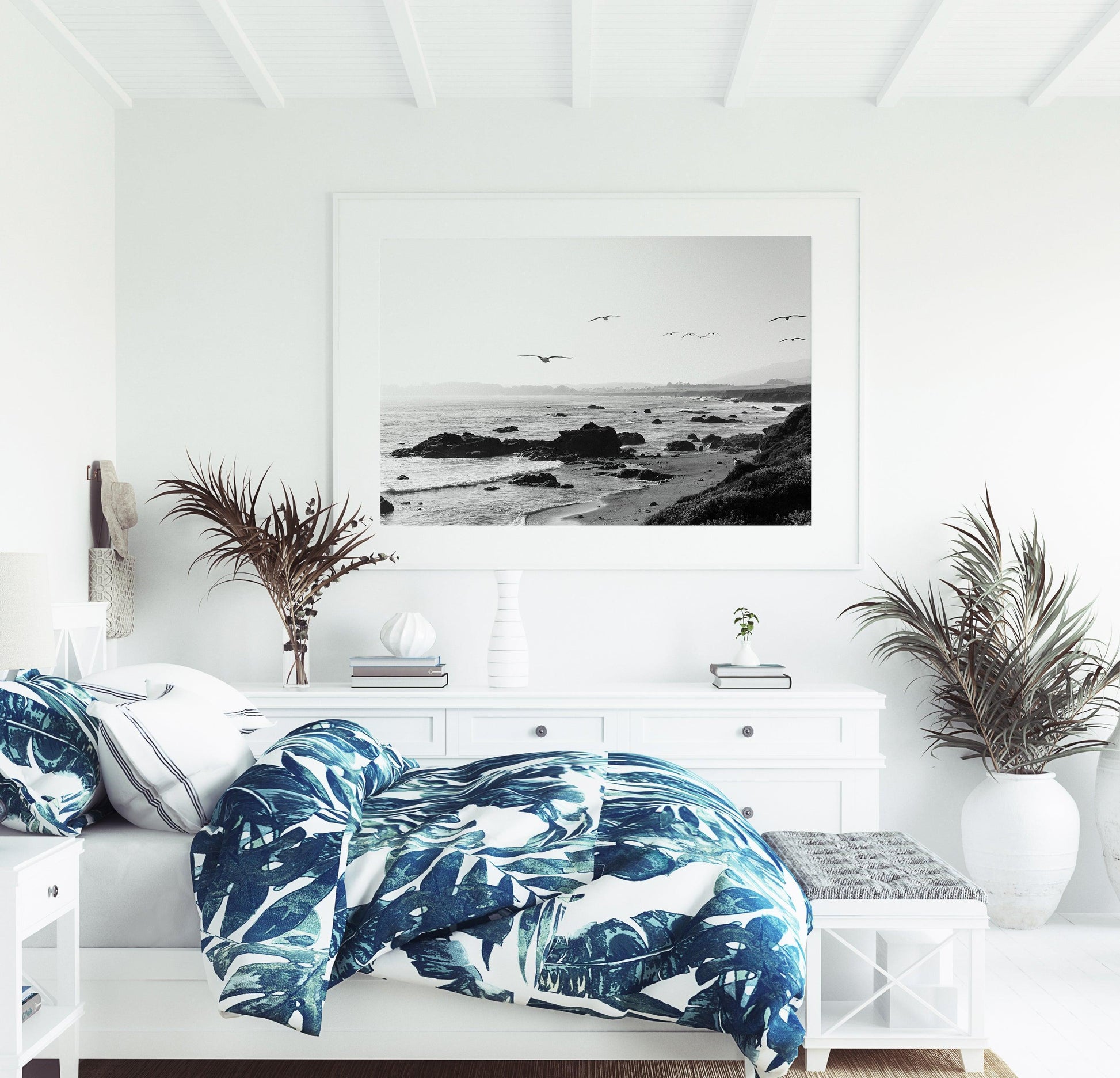 Black and white photo of birds flying over California coast with ocean waves and rocky shoreline