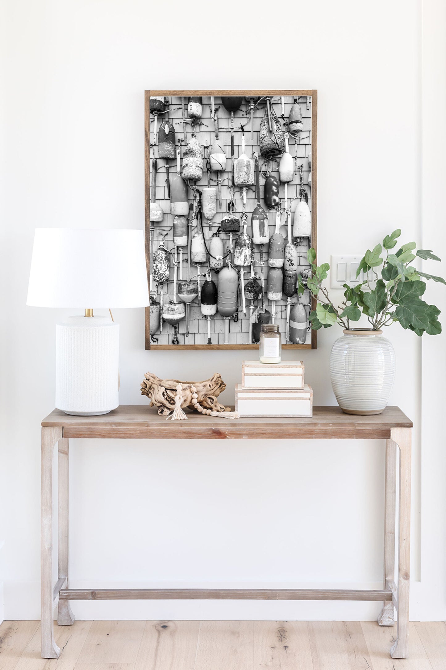 Black and white photograph of weathered fishing buoys hanging on a wood wall, captured in Cape Cod. Nautical wall art with a rustic coastal feel.