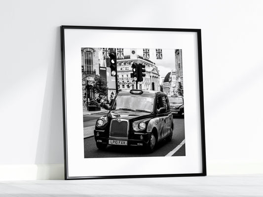 Black and white photograph of a London black cab on city streets, capturing the essence of the city.