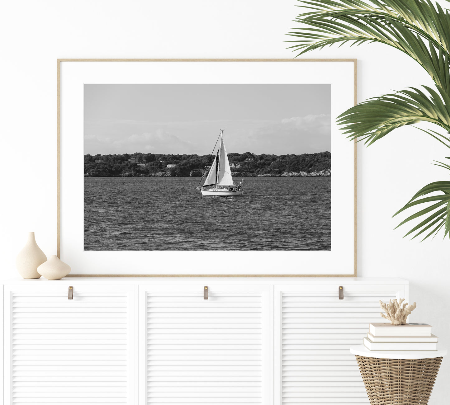 Horizontal black and white sailboat photo taken in Newport, Rhode Island, featuring a single sailboat on open water with a calm shoreline in the background. Ideal for coastal wall decor and lake house art.