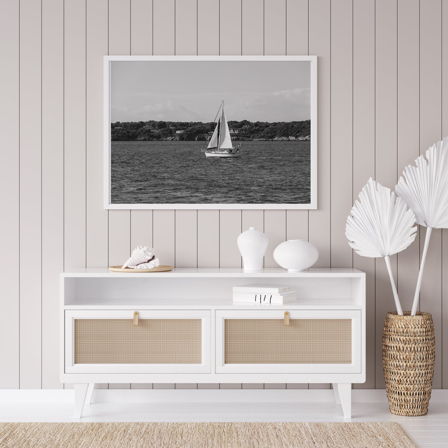 Horizontal black and white sailboat photo taken in Newport, Rhode Island, featuring a single sailboat on open water with a calm shoreline in the background. Ideal for coastal wall decor and lake house art.