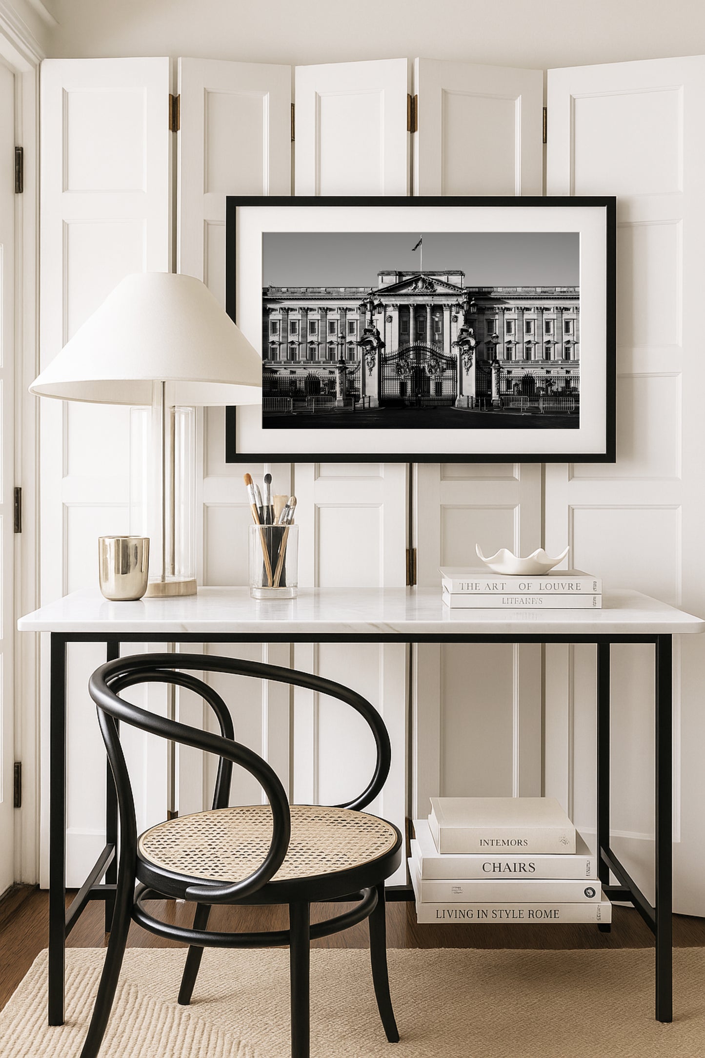 Black and white photograph of Buckingham Palace with decorative gates and clear sky, captured in London.