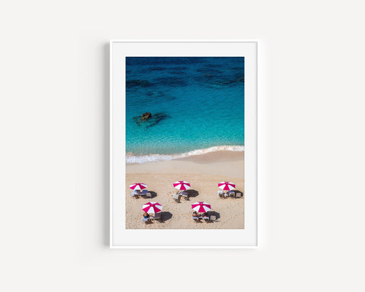Aerial view of five pink beach umbrellas on a Bermuda shoreline with turquoise water