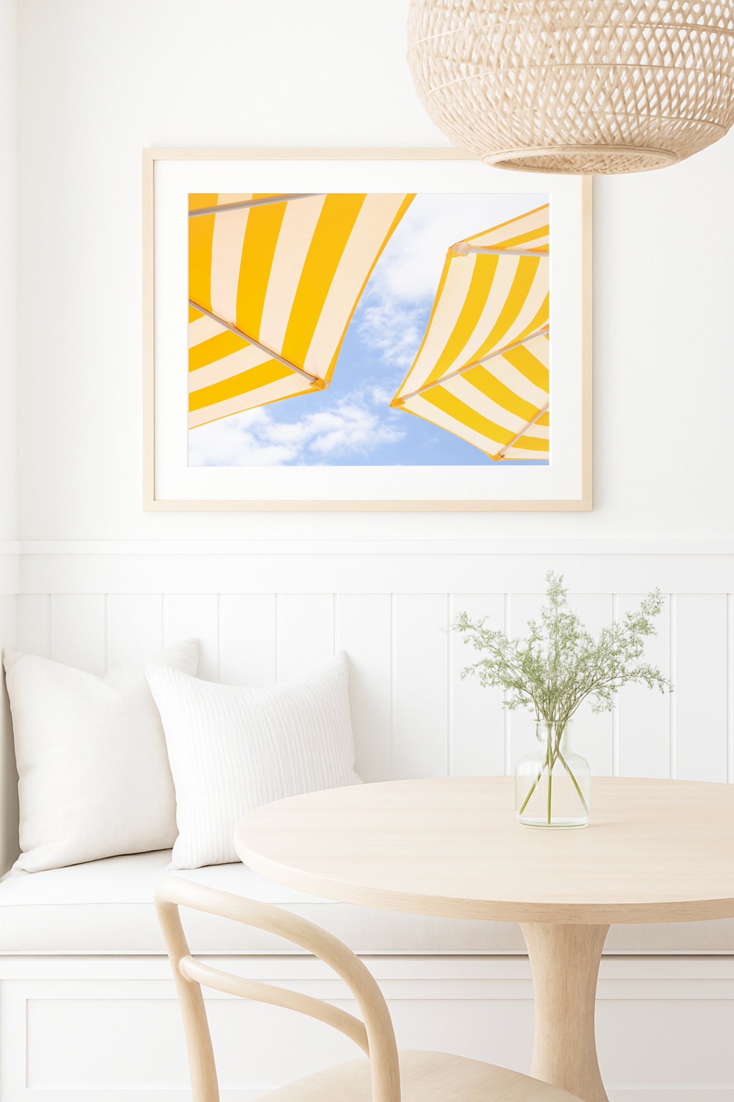 Yellow and white striped beach umbrellas set against a bright blue sky with scattered clouds; minimalist beach photography evoking a sunny coastal vibe.