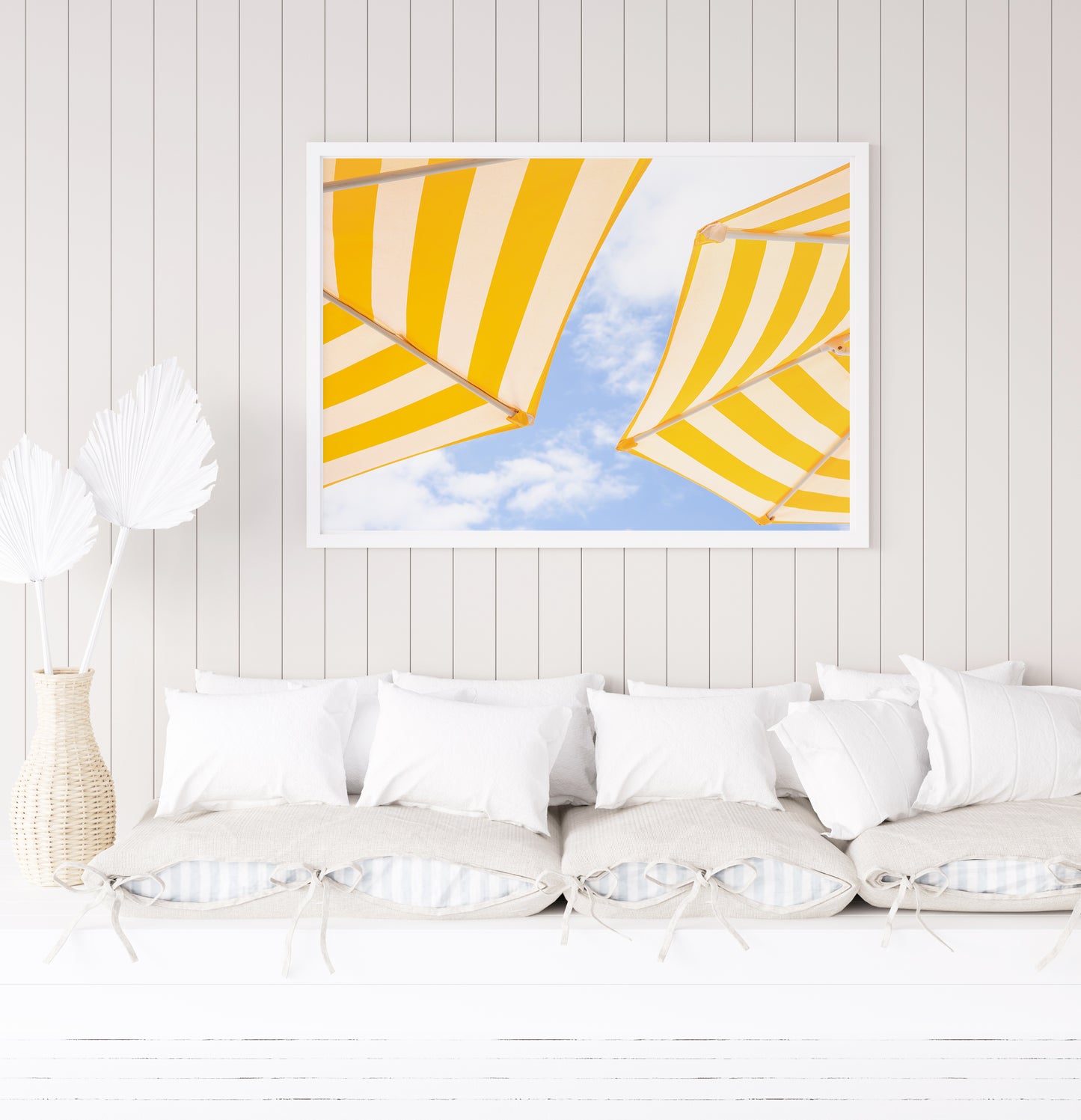 Yellow and white striped beach umbrellas set against a bright blue sky with scattered clouds; minimalist beach photography evoking a sunny Amalfi Coast vibe.