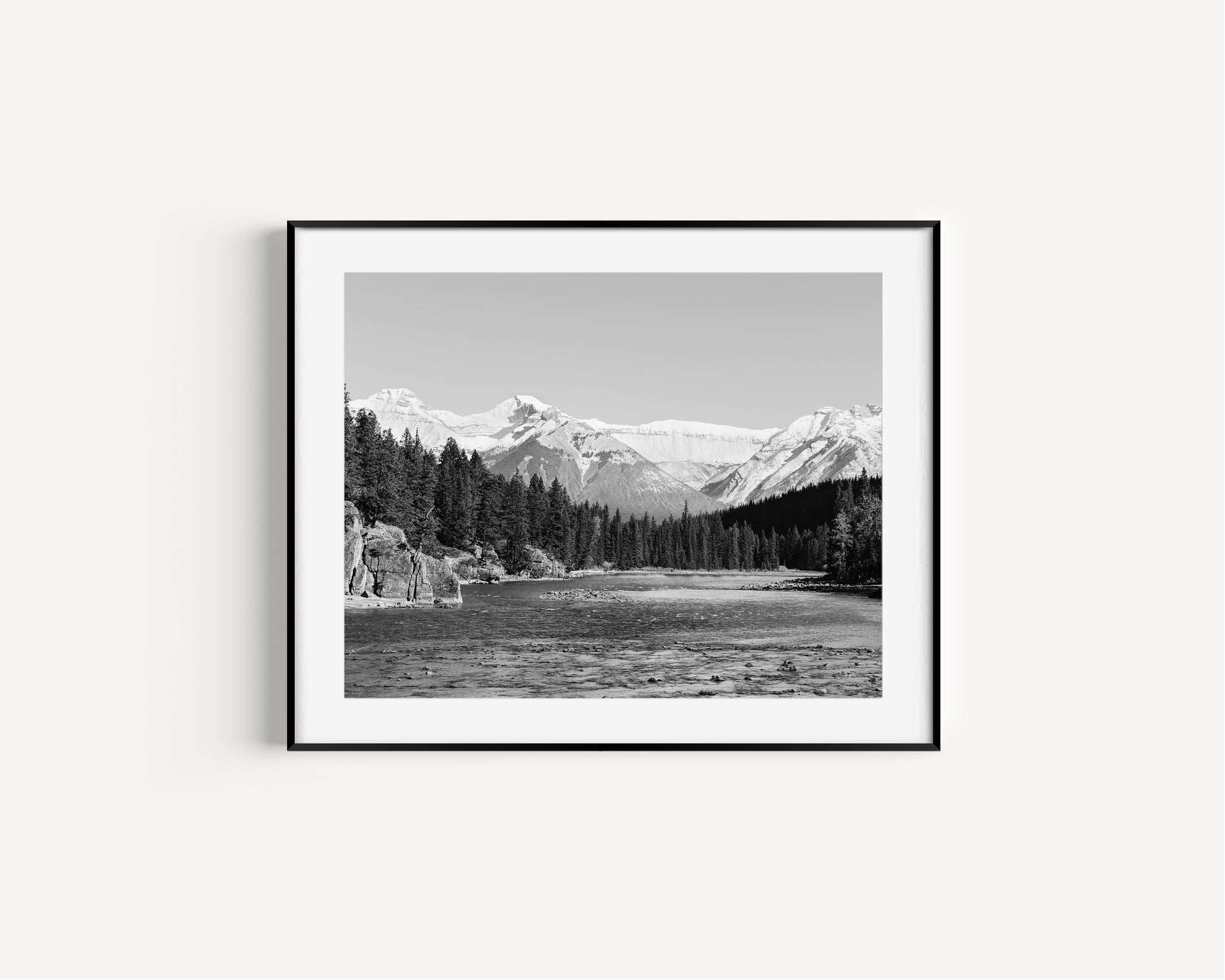 Black and white nature photography print of the Bow River in Banff National Park, with pine trees and Canadian Rockies in Alberta Canada.