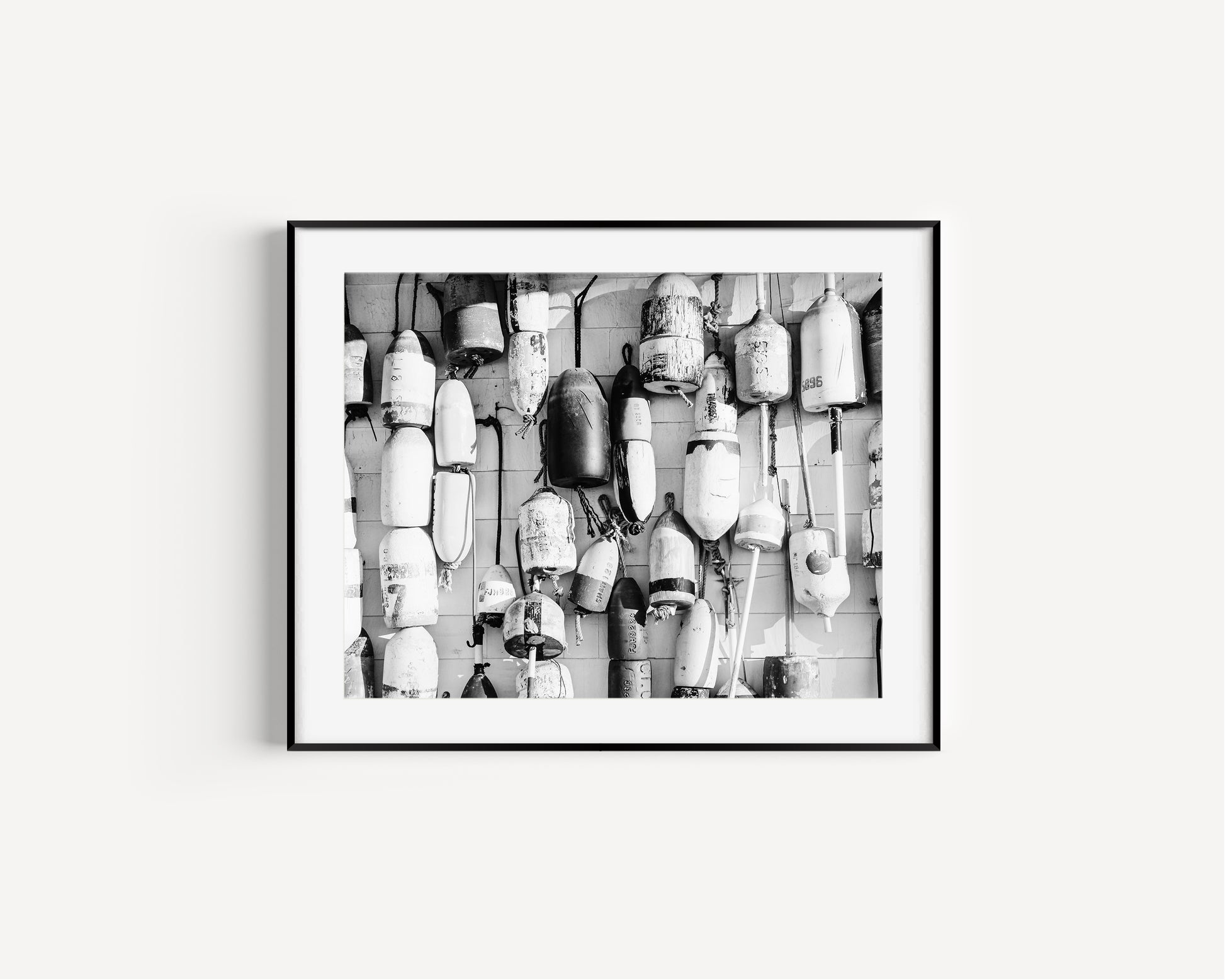 Black and white fine art photograph of weathered lobster buoys hanging on clapboard siding on Cape Cod — densely layered nautical wall art with rich texture and detail