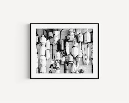 Black and white fine art photograph of weathered lobster buoys hanging on clapboard siding on Cape Cod — densely layered nautical wall art with rich texture and detail