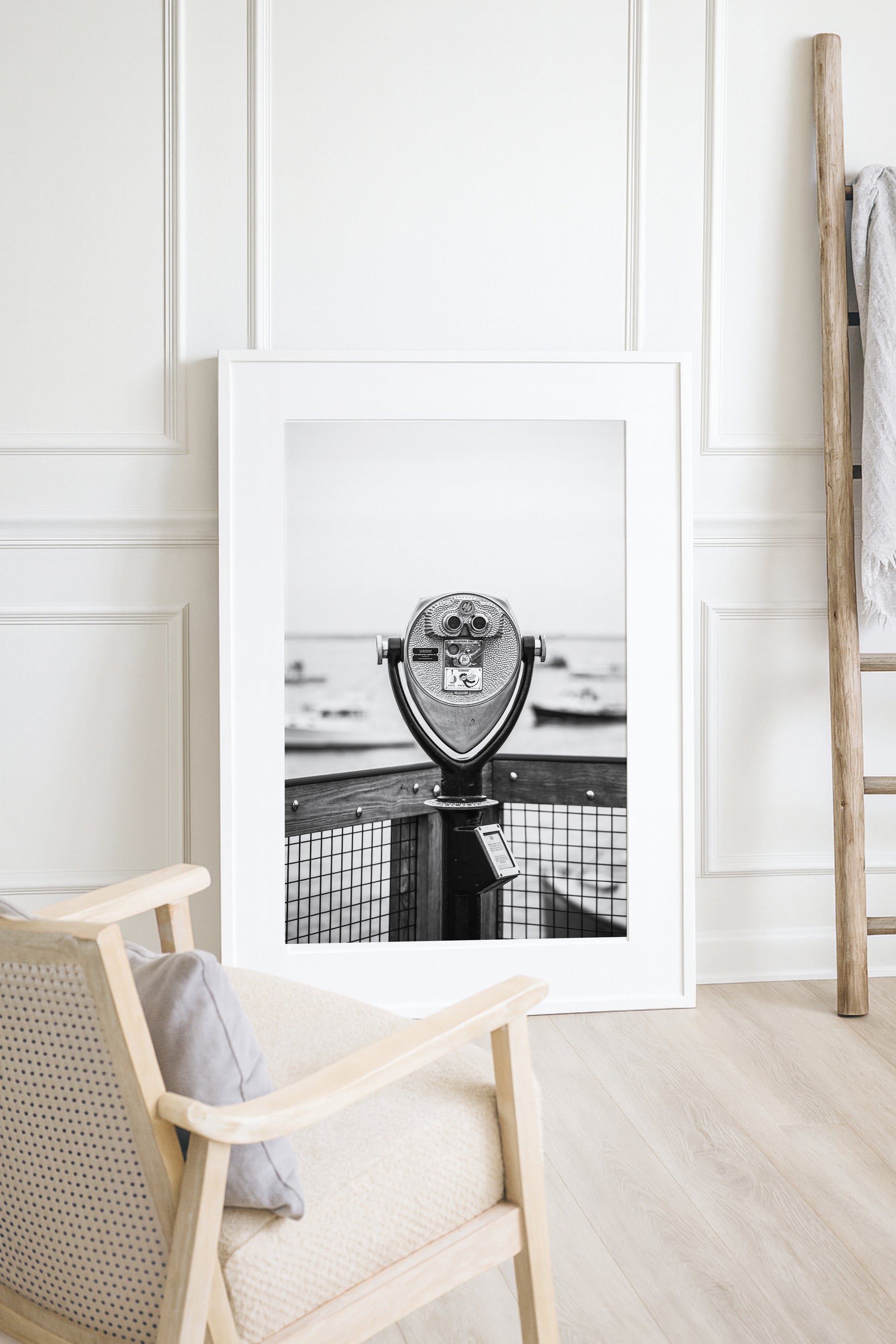 Black and white fine art photograph of a coin-operated viewfinder binoculars on Chatham Pier, Cape Cod — boats soft in the harbor background, wooden pier railing in foreground