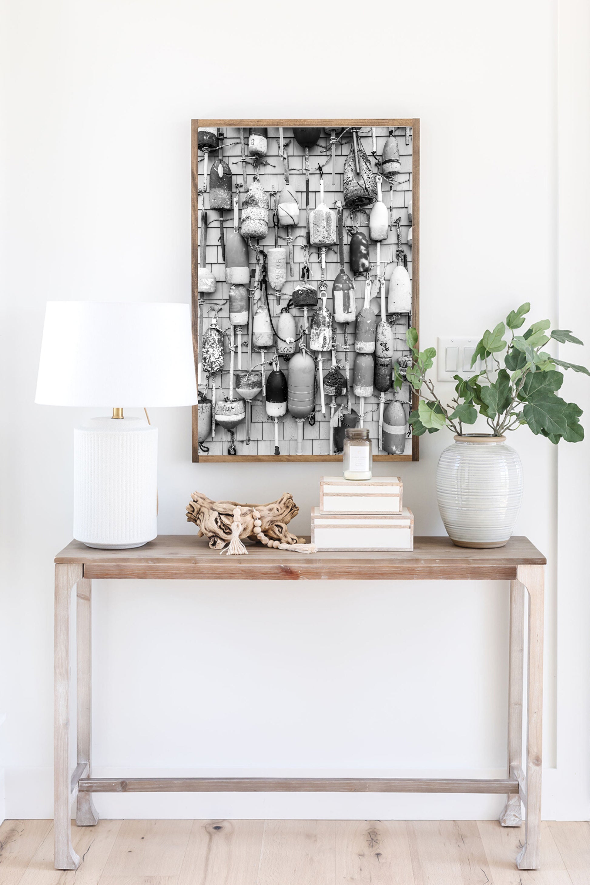 Black and white photograph of weathered fishing buoys hanging on a wood wall, captured in Cape Cod. Nautical wall art with a rustic coastal feel.