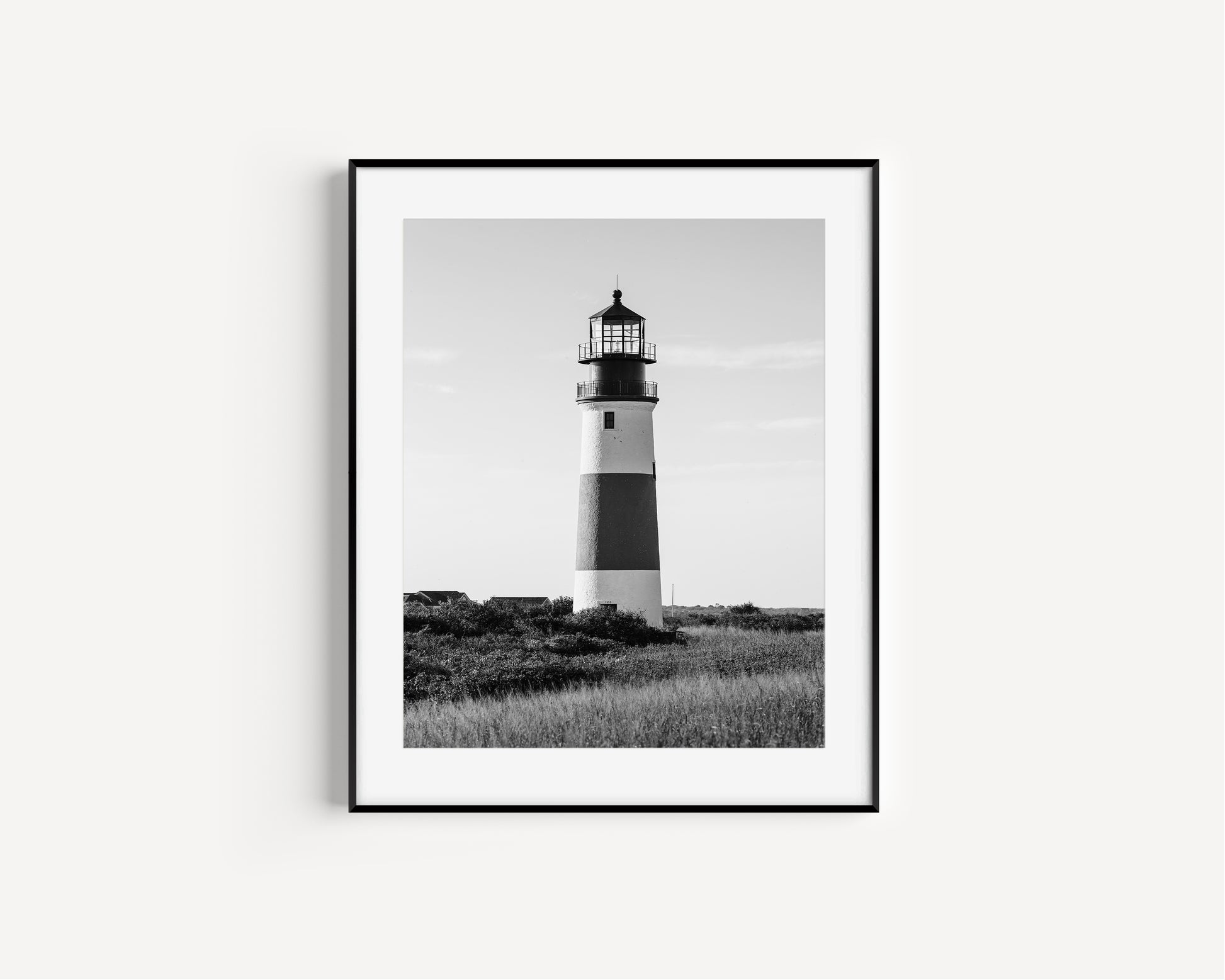 Black and white fine art photograph of Sankaty Head Lighthouse on Nantucket Island — banded tower rising above wild moor grass against an open sky in Siasconset