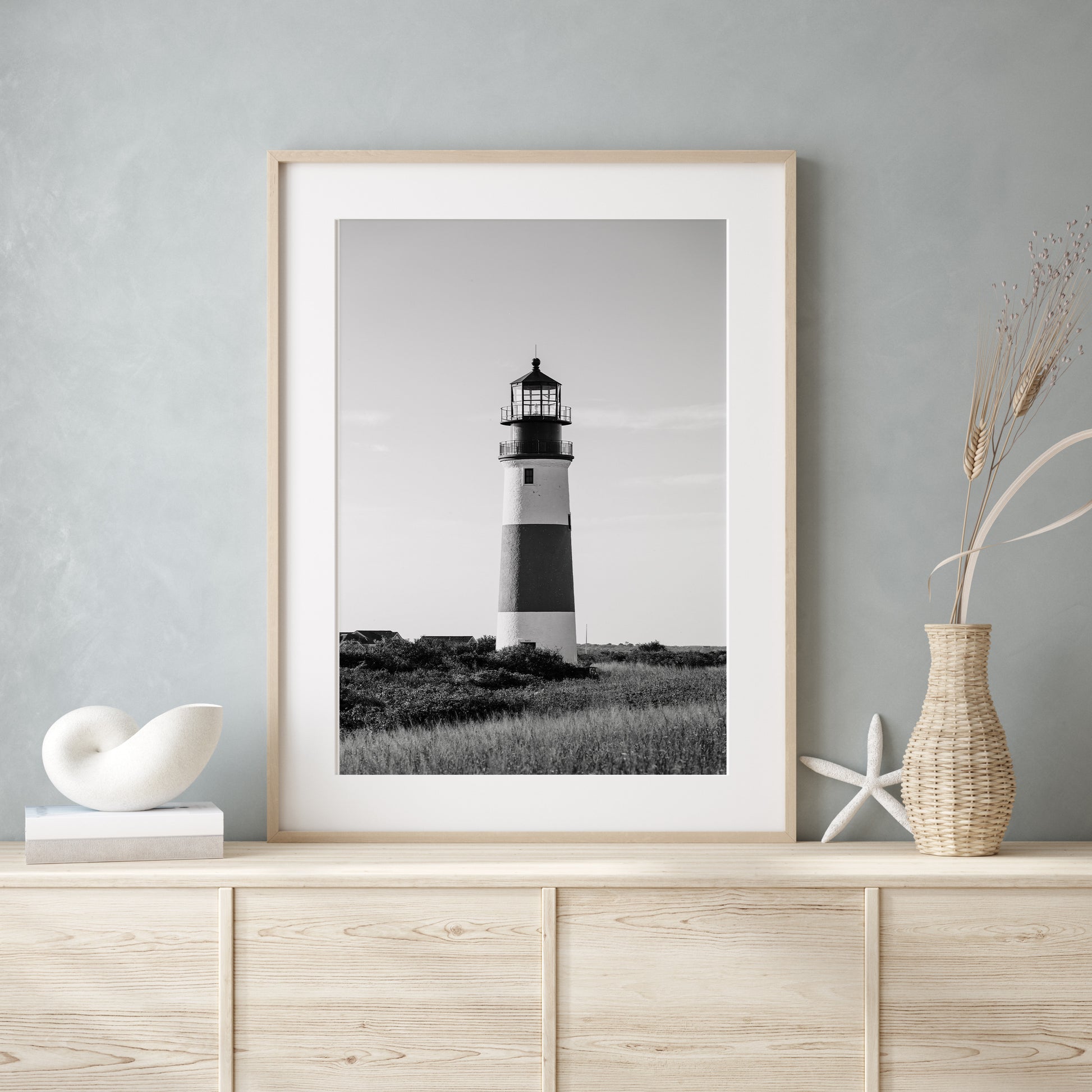 Black and white fine art photograph of Sankaty Head Lighthouse on Nantucket Island — banded tower rising above wild moor grass against an open sky in Siasconset