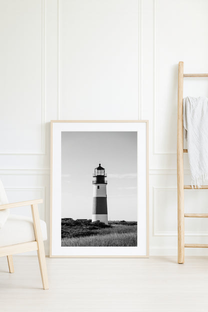 Black and white fine art photograph of Sankaty Head Lighthouse on Nantucket Island — banded tower rising above wild moor grass against an open sky in Siasconset