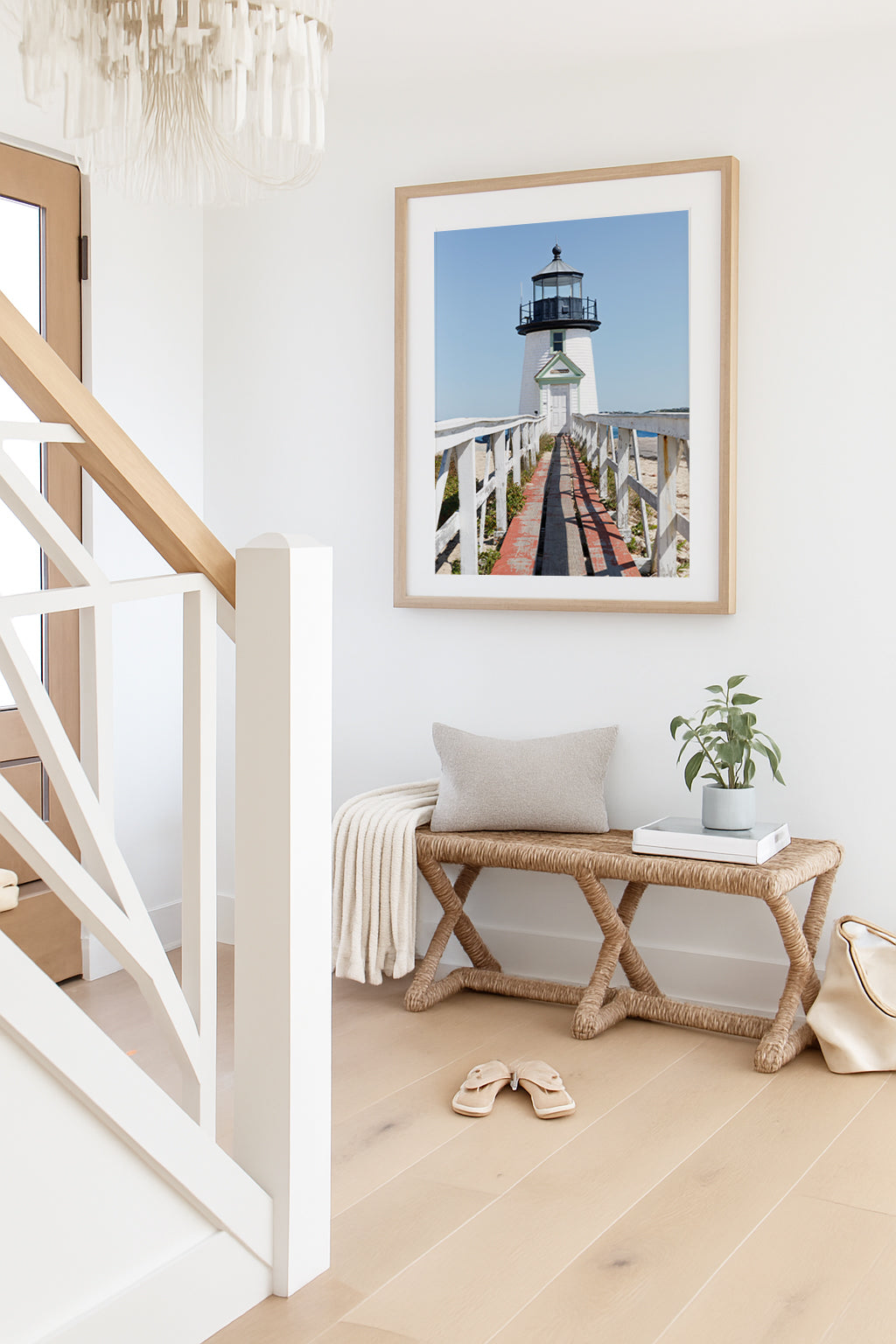 Vertical photograph of Brant Point Lighthouse in Nantucket, viewed straight down the weathered boardwalk with a bright blue sky and soft coastal light.