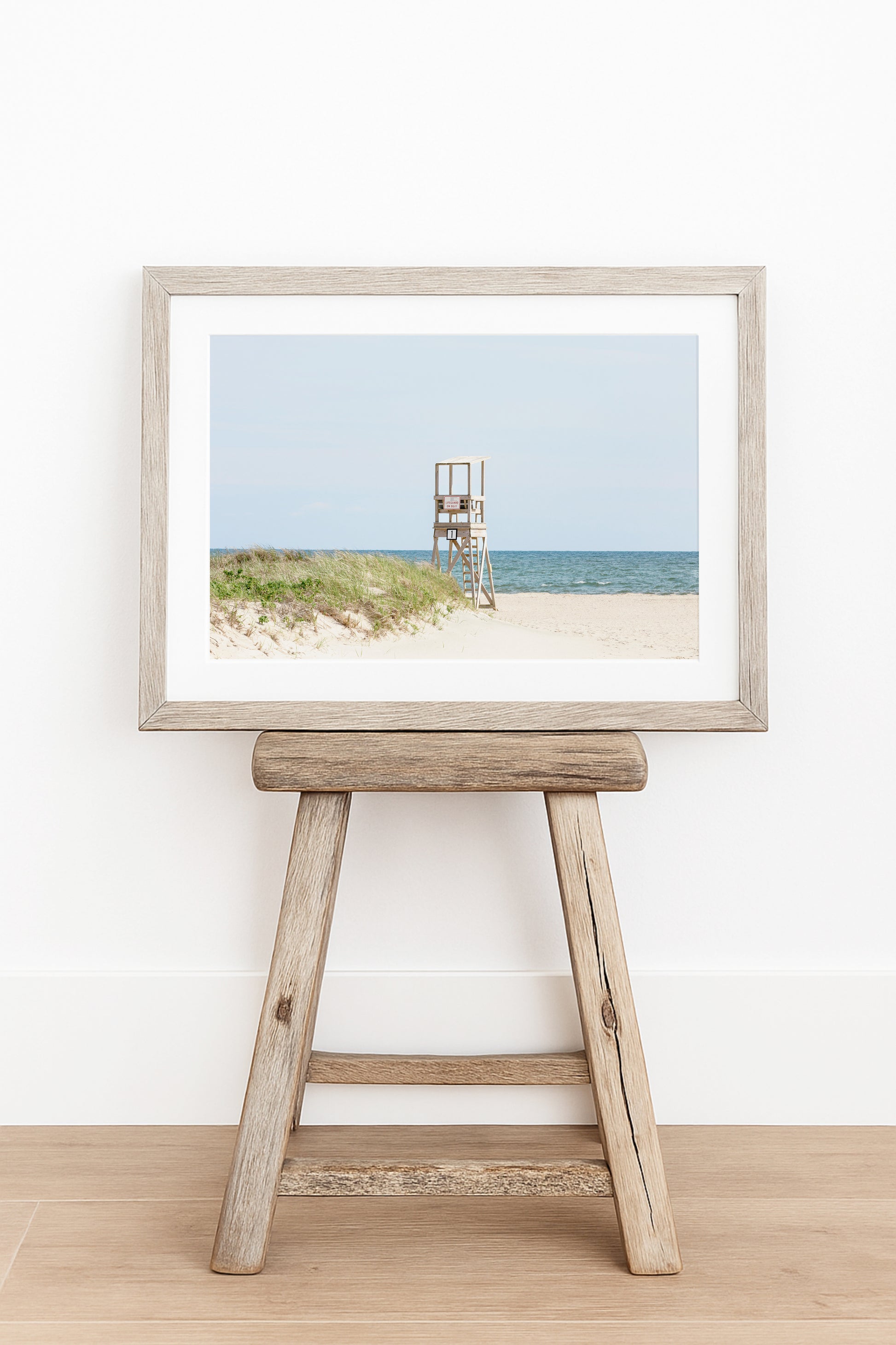 Color fine art photograph of an empty lifeguard stand at Bank Street Beach on Cape Cod — rolling sand dunes, sea grass, and the open Atlantic under a pale summer sky