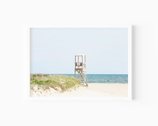 Color fine art photograph of an empty lifeguard stand at Bank Street Beach on Cape Cod — rolling sand dunes, sea grass, and the open Atlantic under a pale summer sky
