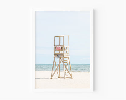 Color fine art photograph of an empty wooden lifeguard tower at Bank Street Beach in Harwich, Cape Cod — white sand and blue-green Atlantic in the background