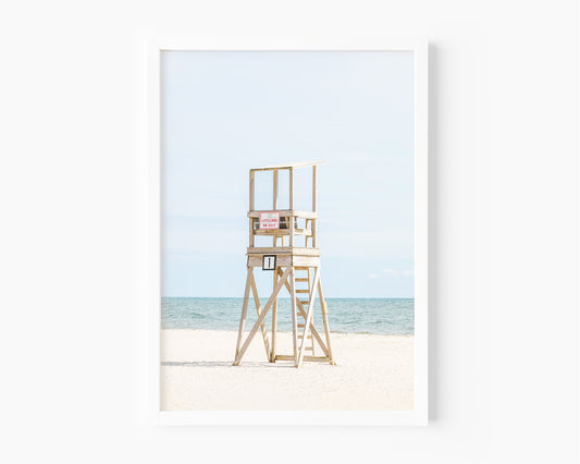 Color fine art photograph of an empty wooden lifeguard tower at Bank Street Beach in Harwich, Cape Cod — white sand and blue-green Atlantic in the background