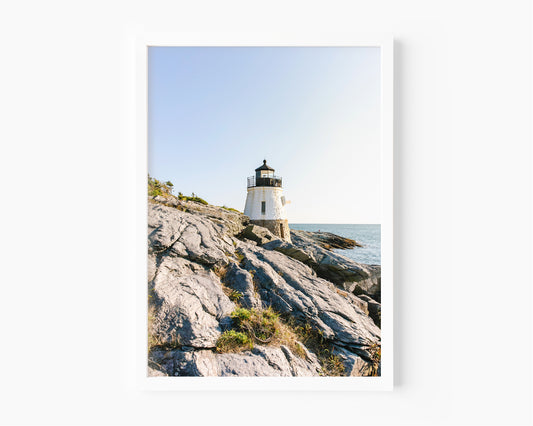 Castle Hill Lighthouse perched on rocky Rhode Island coastline under a clear sky, captured in golden hour light – Newport RI photo print for beach and coastal decor.