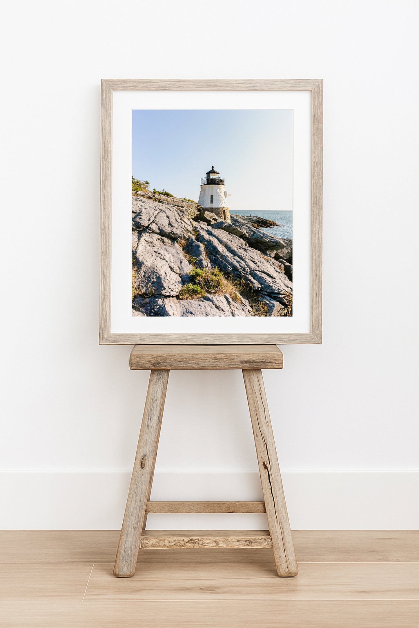 Castle Hill Lighthouse perched on rocky Rhode Island coastline under a clear sky, captured in golden hour light – Newport RI photo print for beach and coastal decor.