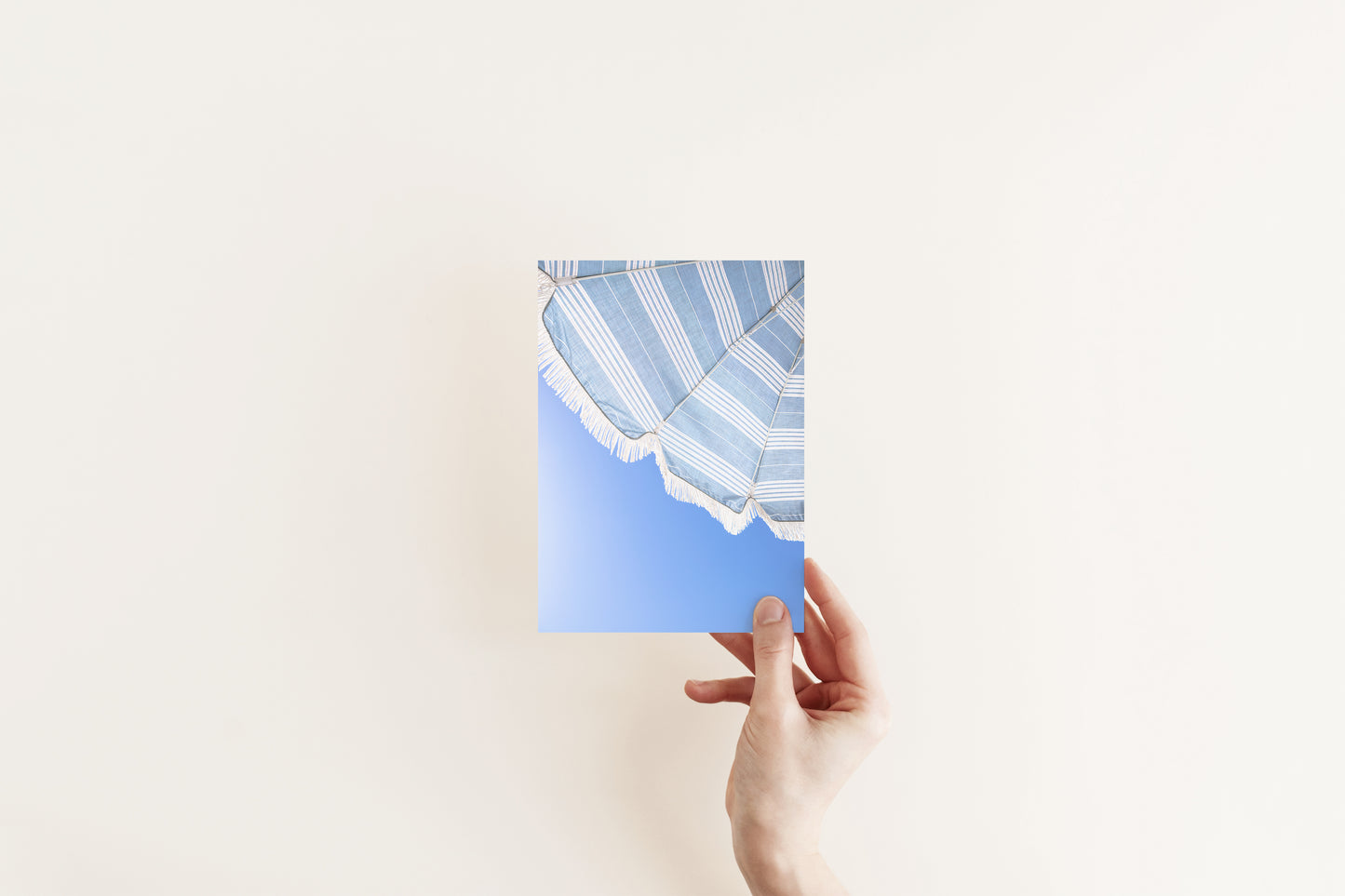 Vertical photo of striped blue beach umbrella with fringe and bright blue sky – coastal summer wall art