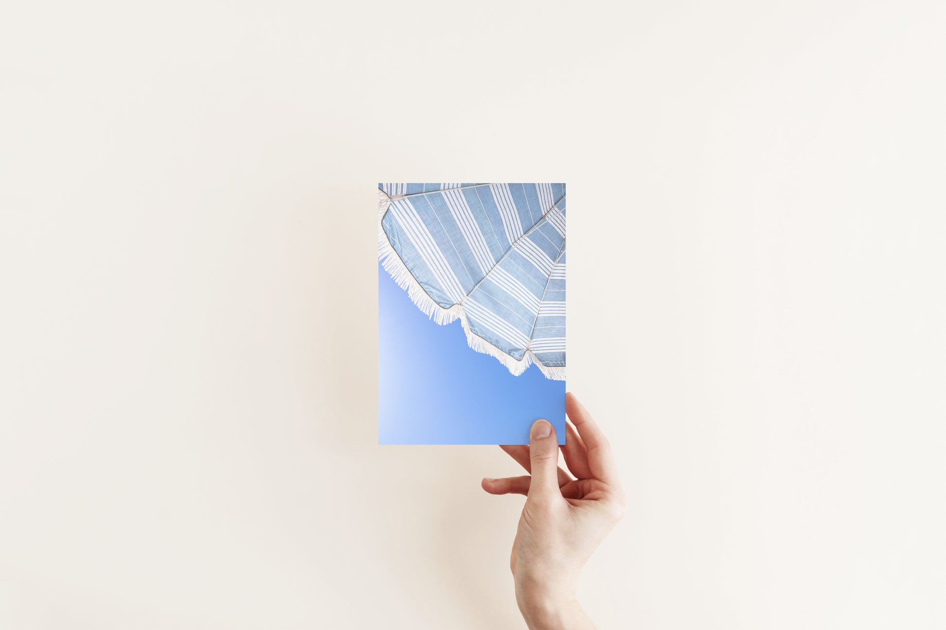 Vertical photo of striped blue beach umbrella with fringe and bright blue sky – coastal summer wall art