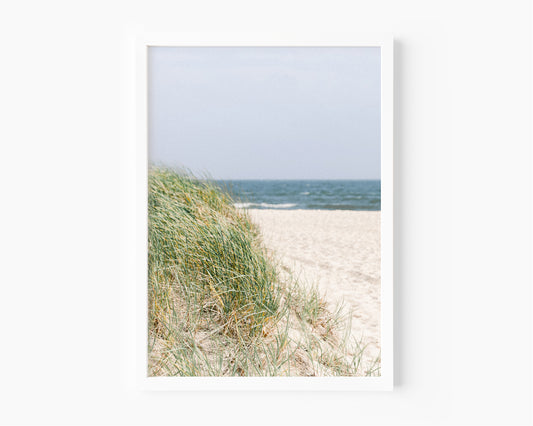 Neutral-toned beach photography of sand dunes and beach grass under a pale sky, evoking a coastal New England feel with a Nantucket aesthetic