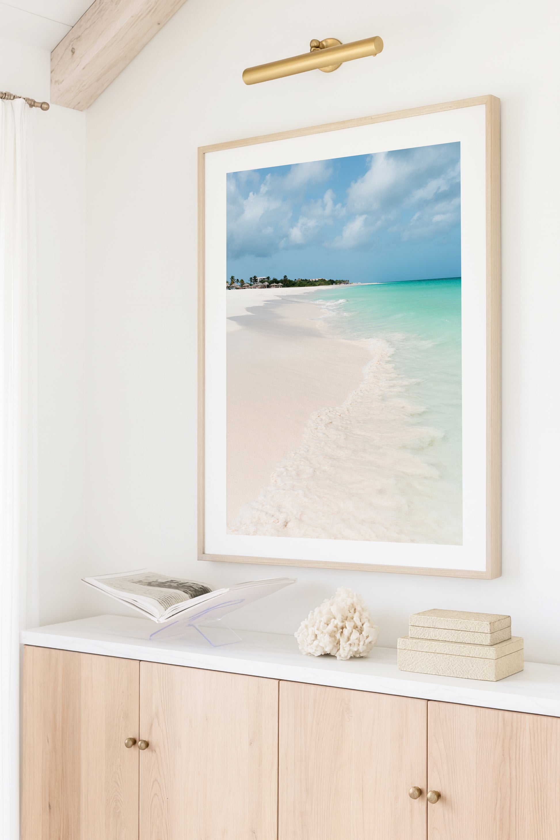 Color fine art photograph of Eagle Beach in Aruba — powder white sand, turquoise Caribbean water with a gentle wave at the shoreline, and palapa huts visible in the distance