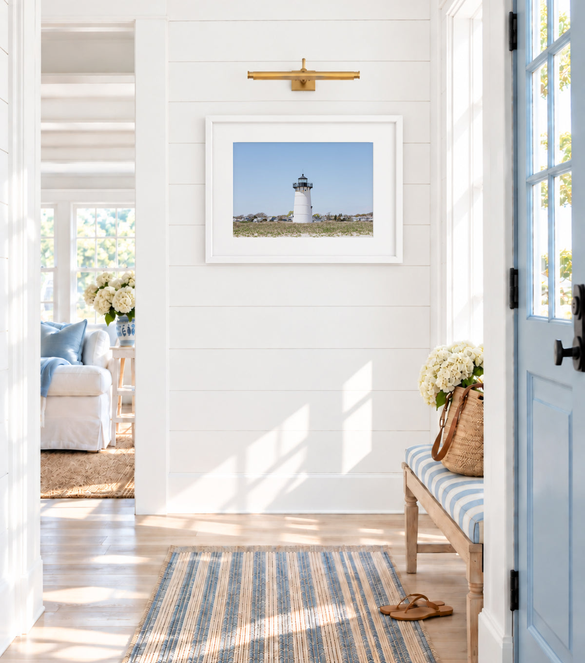 Color fine art photograph of the Edgartown Lighthouse on Martha's Vineyard, white tower centered against a pale blue sky with beach grass in the foreground and Edgartown village behind it