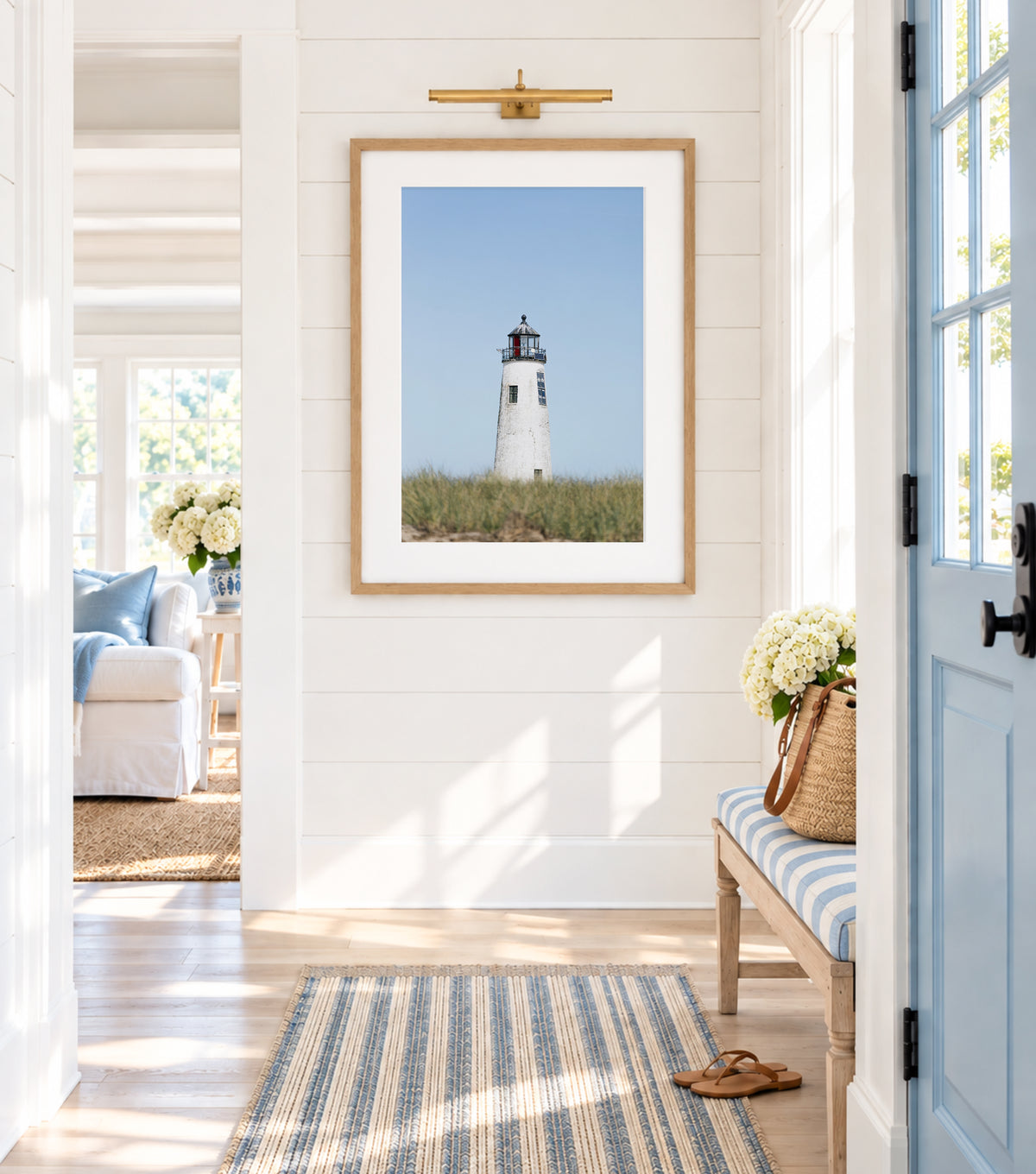 Color fine art photograph of Great Point Lighthouse on Nantucket Island — weathered white tower centered against a wide pale blue sky with dune grass at the base, minimalist coastal wall art