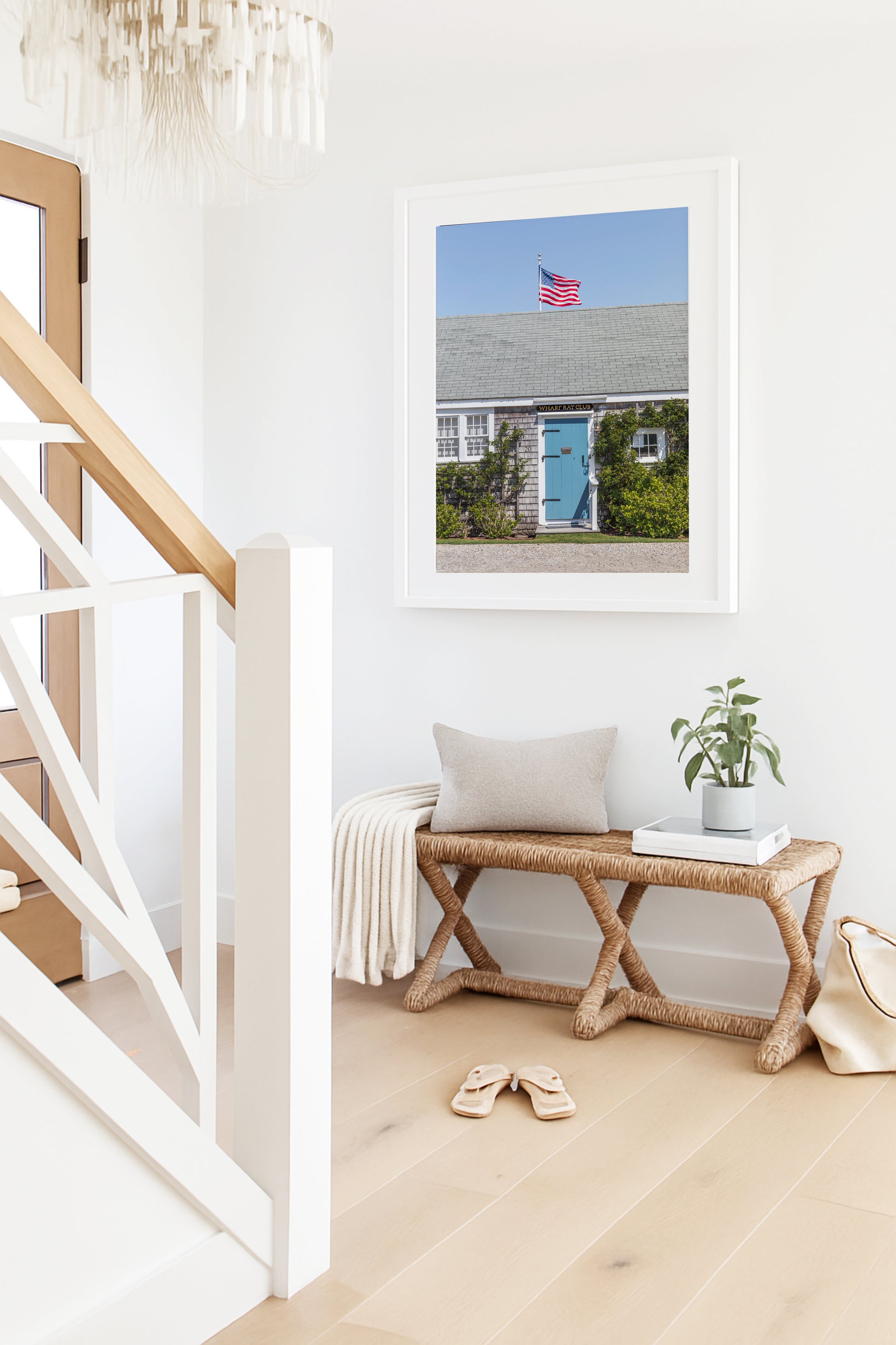 Color fine art photograph of the Wharf Rat Club on Nantucket — weathered grey shingle cottage with a powder blue door, climbing vines, and an American flag flying above the roofline against a blue summer sky