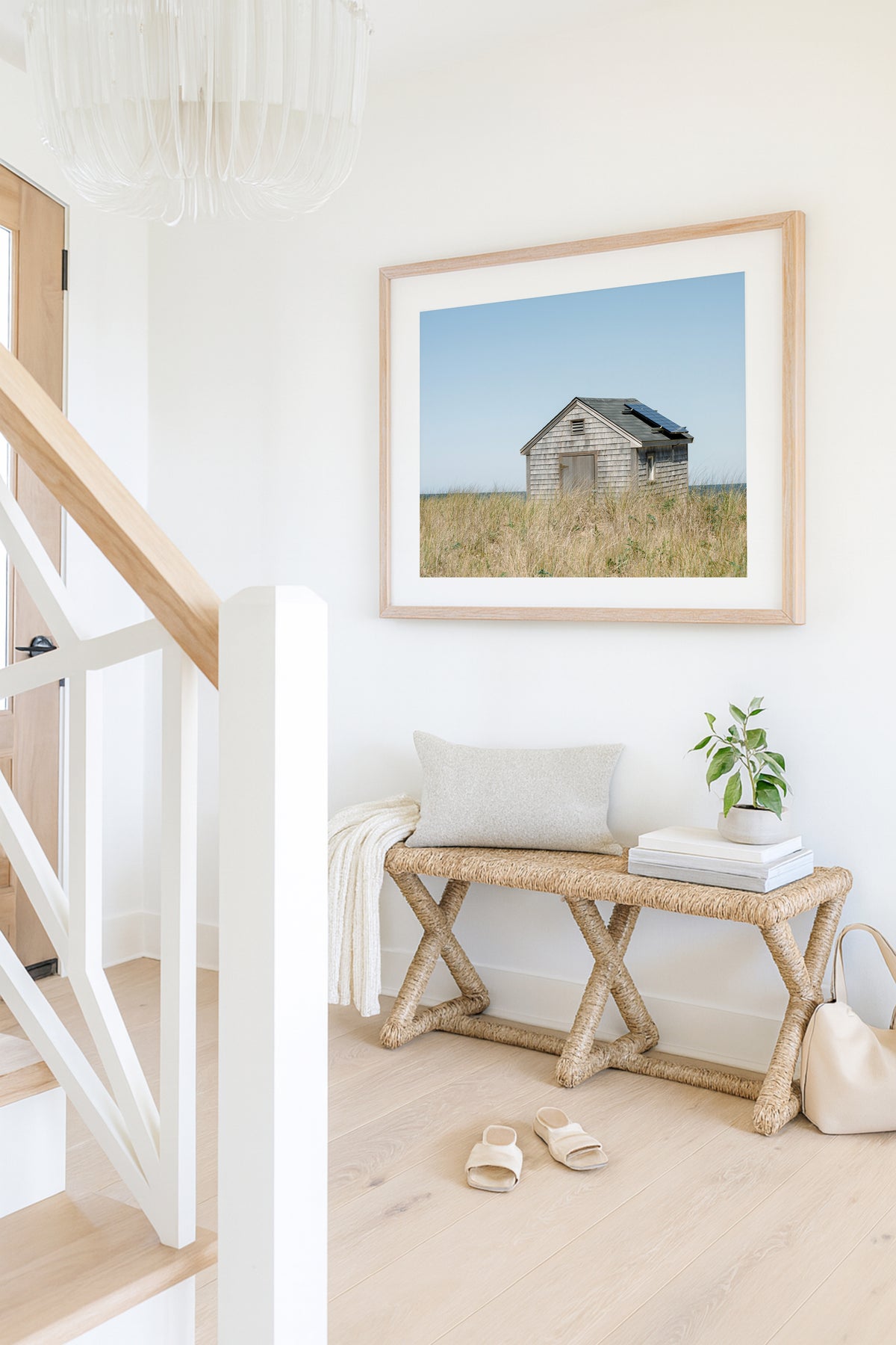 Color fine art photograph of a weathered grey shingle beach cottage alone in golden dune grass on Nantucket Island — ocean visible on the horizon under a wide pale blue sky