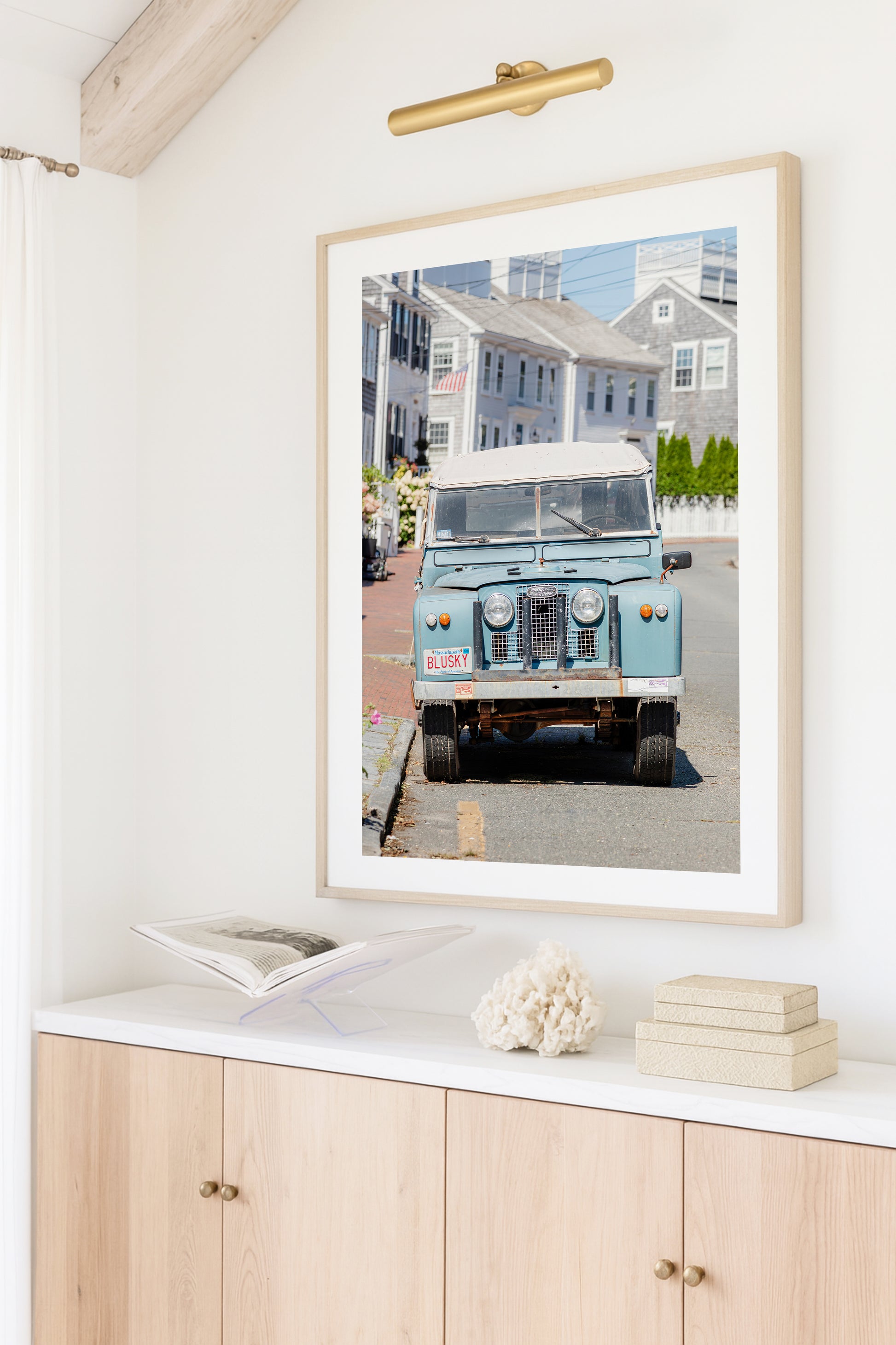 Color fine art photograph of a vintage powder blue Land Rover Series parked on a cobblestone street in Nantucket — Massachusetts vanity plate BLUSKY, grey shingle cottages and hydrangeas in the background