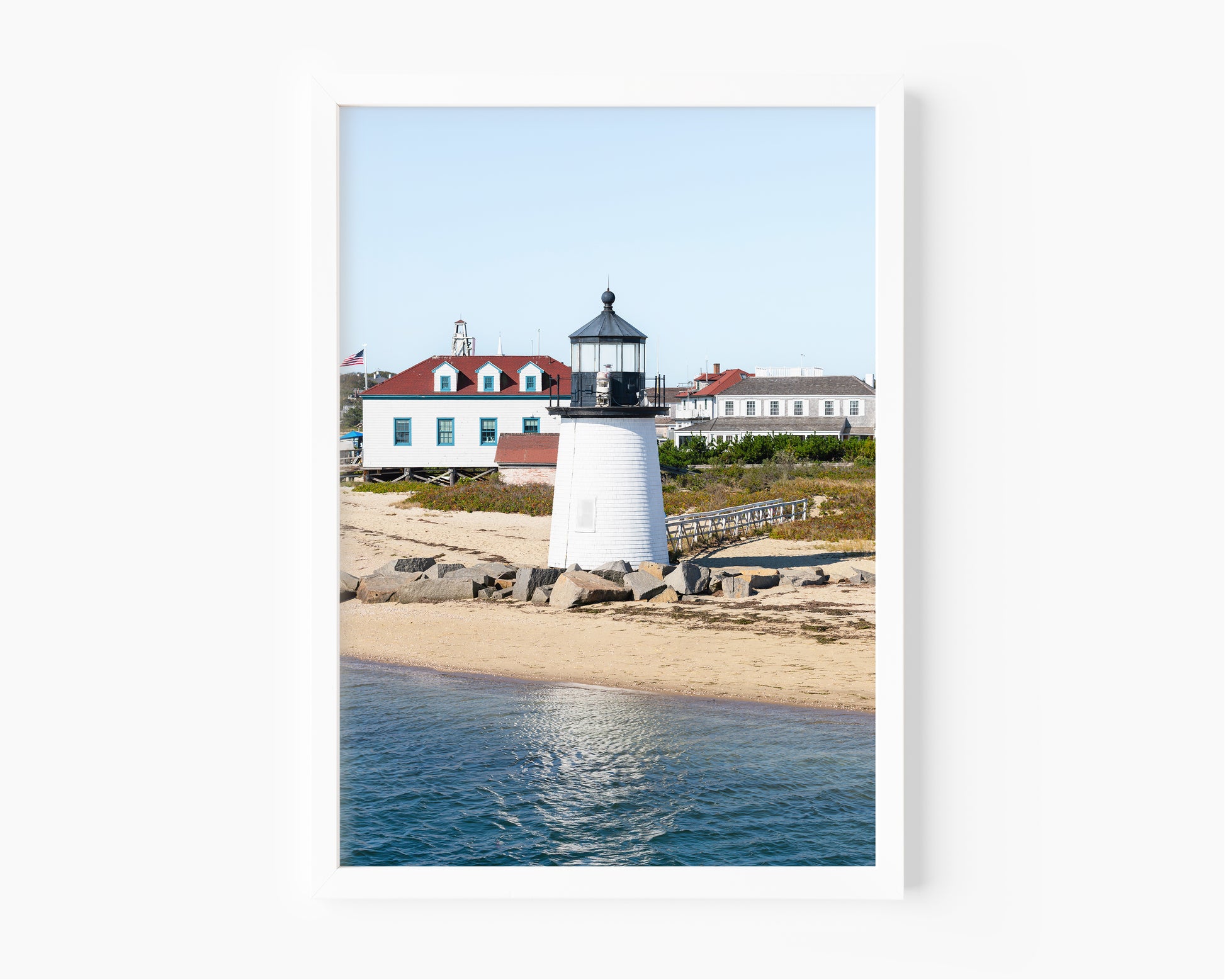 Brant Point Lighthouse print in Nantucket, featuring a white tower, rocky shoreline, and blue sky—ideal for nautical and coastal wall decor.
