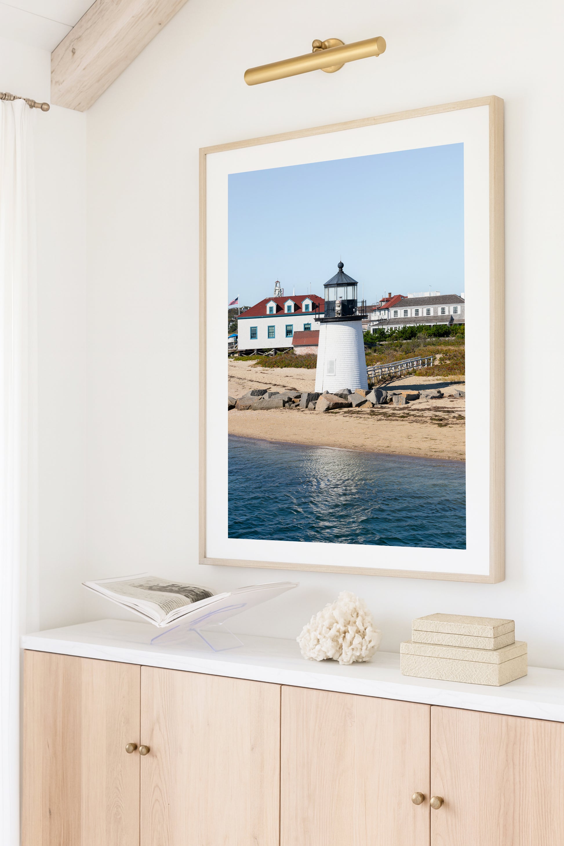 Brant Point Lighthouse print in Nantucket, featuring a white tower, rocky shoreline, and blue sky—ideal for nautical and coastal wall decor.