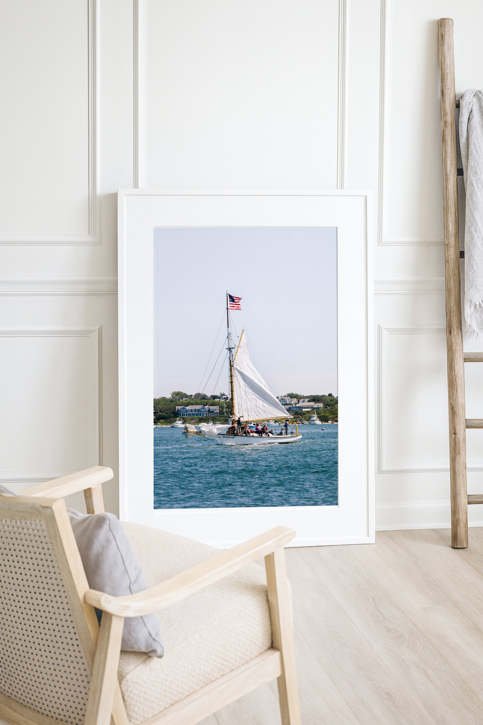 Sailboat cruising in Nantucket Harbor with white sails raised and an American flag flying, photographed on a clear summer day along the New England coastline.