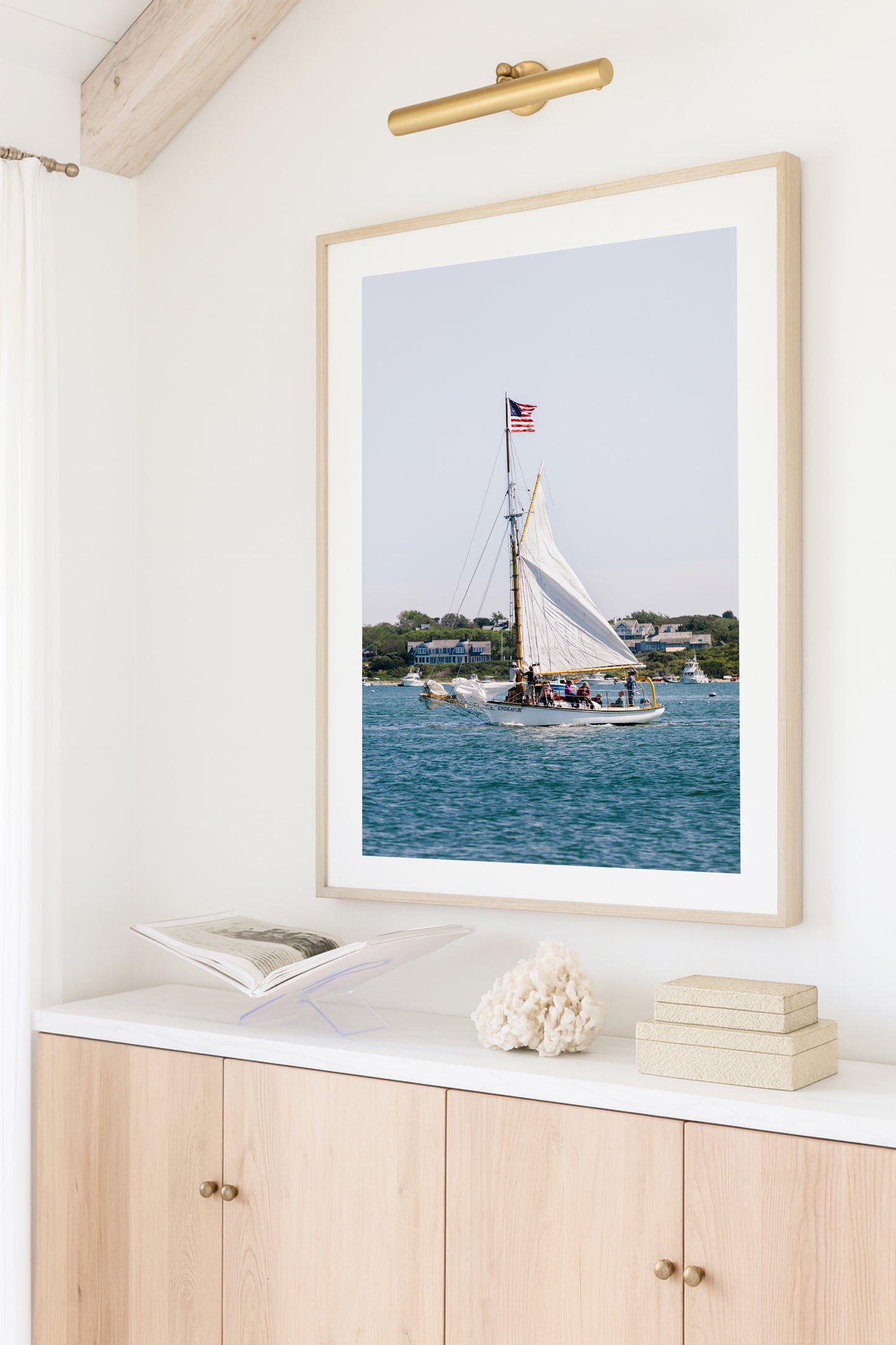 Sailboat cruising in Nantucket Harbor with white sails raised and an American flag flying, photographed on a clear summer day along the New England coastline.