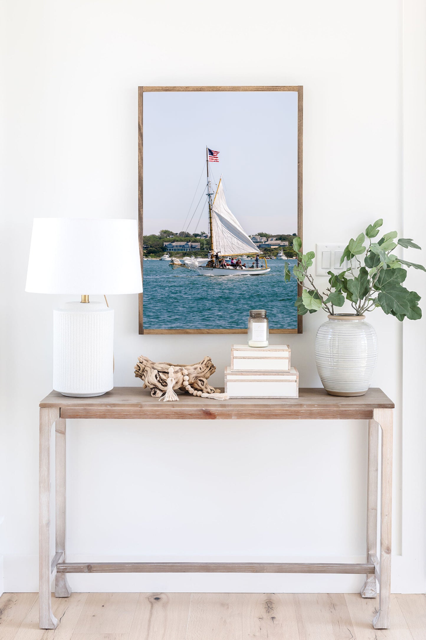 Sailboat cruising in Nantucket Harbor with white sails raised and an American flag flying, photographed on a clear summer day along the New England coastline.