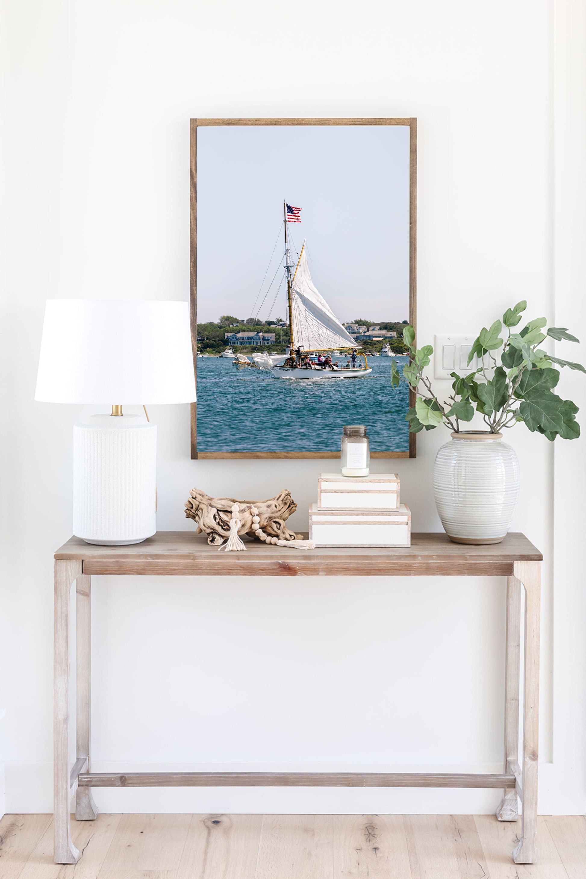 Sailboat cruising in Nantucket Harbor with white sails raised and an American flag flying, photographed on a clear summer day along the New England coastline.