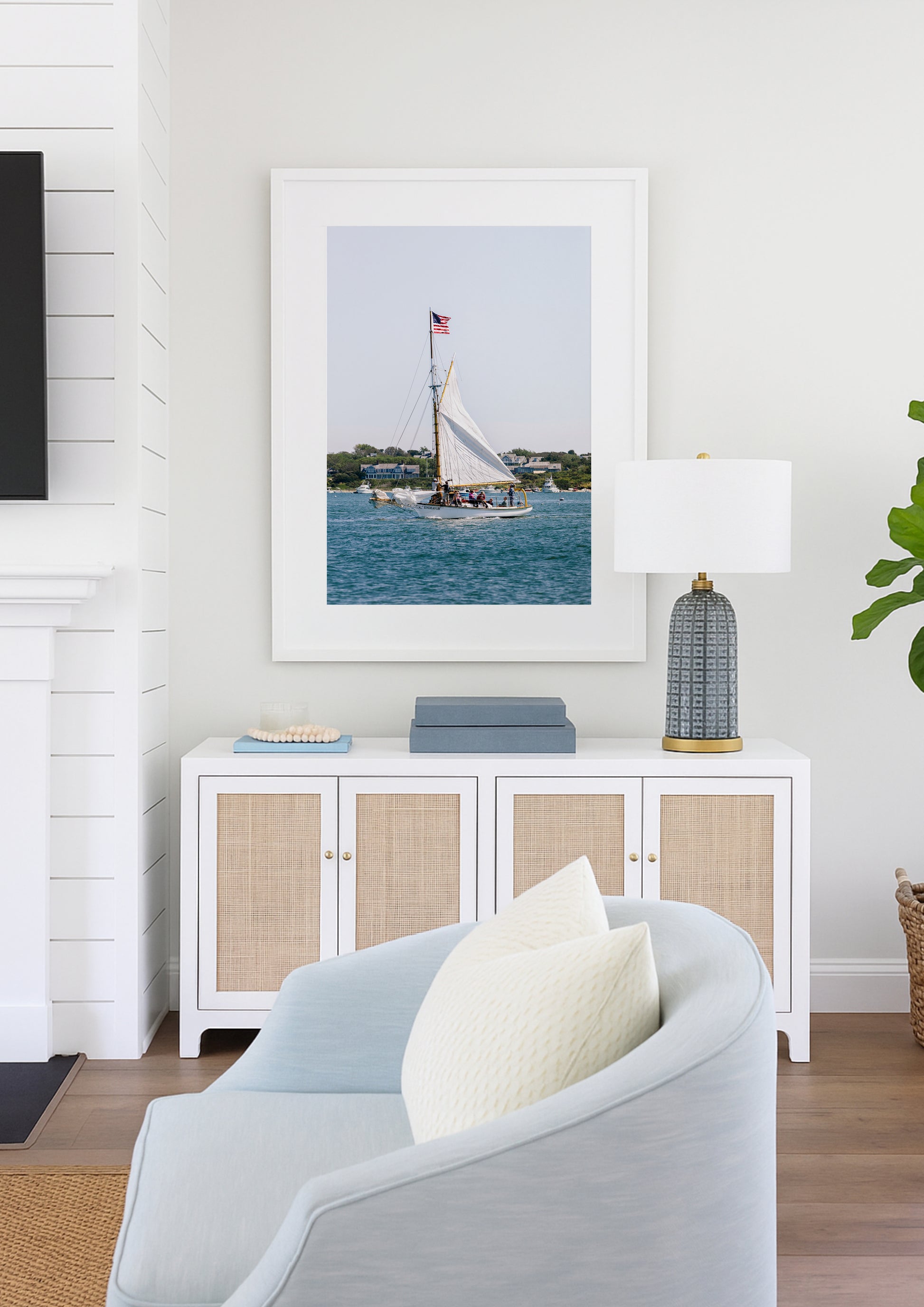 Sailboat cruising in Nantucket Harbor with white sails raised and an American flag flying, photographed on a clear summer day along the New England coastline.