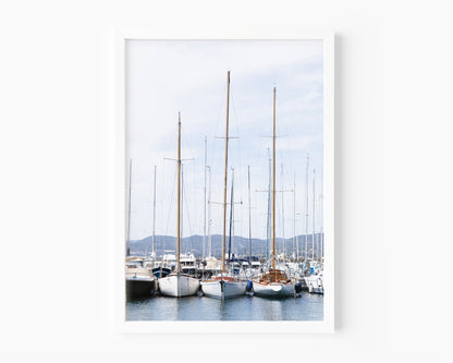 A neutral-toned sailboat moored in a calm New England harbor on a clear day