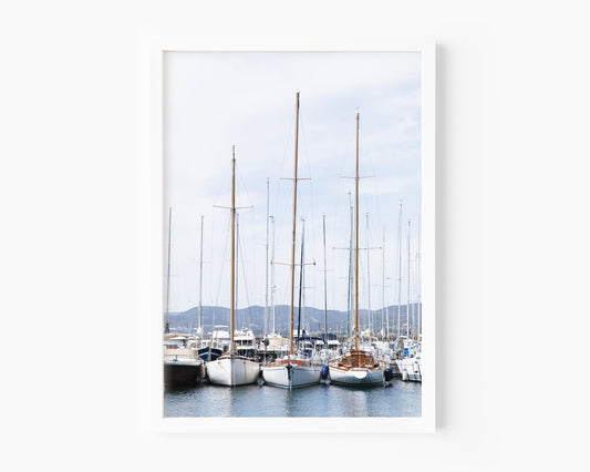 A neutral-toned sailboat moored in a calm New England harbor on a clear day