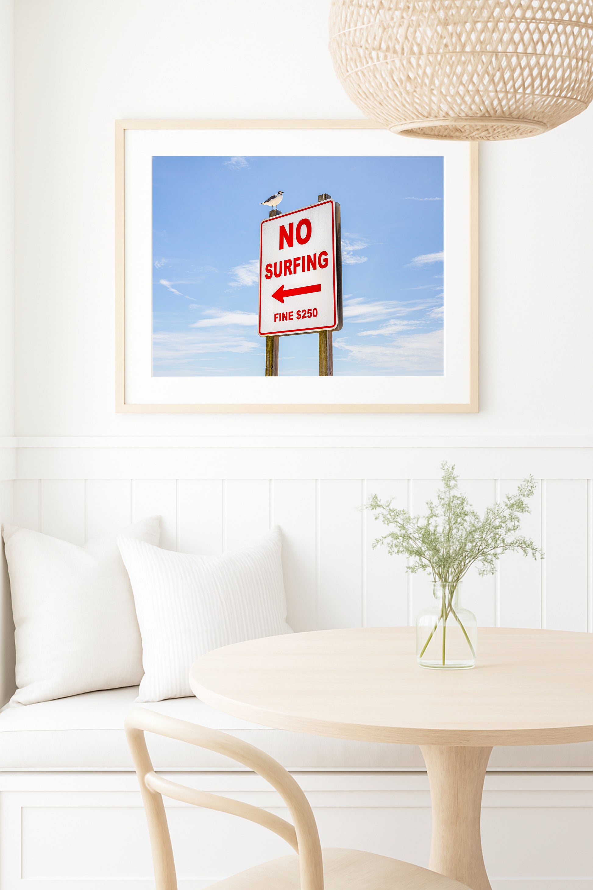 Color fine art photograph of a red and white No Surfing Fine $250 sign at Wrightsville Beach in Wilmington, North Carolina — a seagull perched on top of the sign against a blue sky