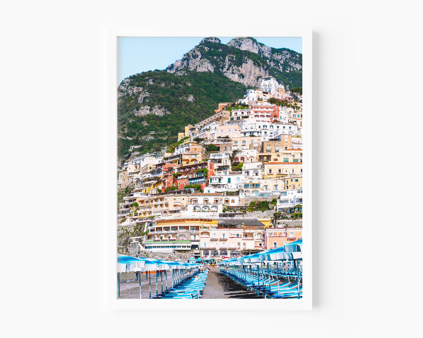Rows of blue and white beach umbrellas and loungers on Spiaggia Grande with the colorful hillside buildings of Positano stacked up the cliffside, Amalfi Coast, Italy