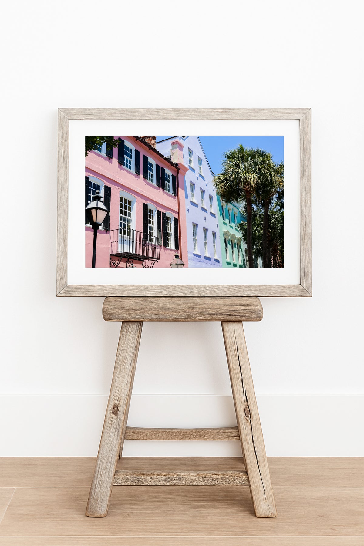 Color fine art photograph of Rainbow Row on East Bay Street in Charleston, South Carolina — pink, lavender, and mint green pastel facades with wrought iron balconies and palm trees against a blue sky