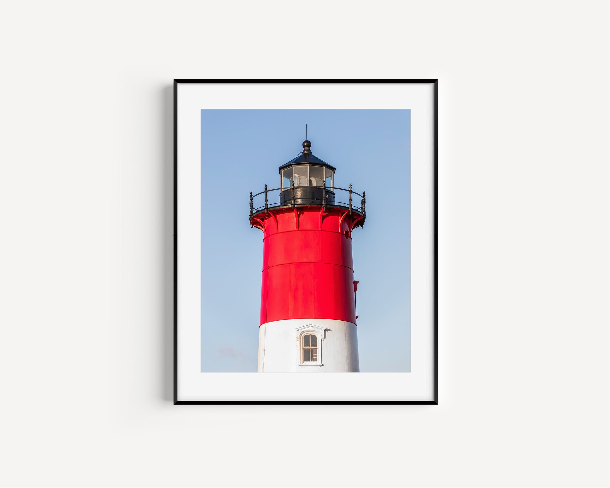 Vertical photograph of the red and white Nauset Lighthouse in Eastham, Massachusetts, set against a clear blue sky with no dunes or beach in view