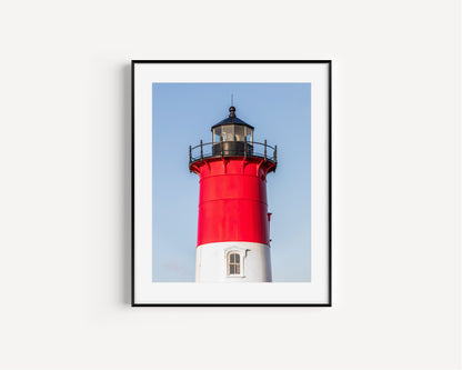Vertical photograph of the red and white Nauset Lighthouse in Eastham, Massachusetts, set against a clear blue sky with no dunes or beach in view