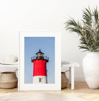 Vertical photograph of the red and white Nauset Lighthouse in Eastham, Massachusetts, set against a clear blue sky with no dunes or beach in view